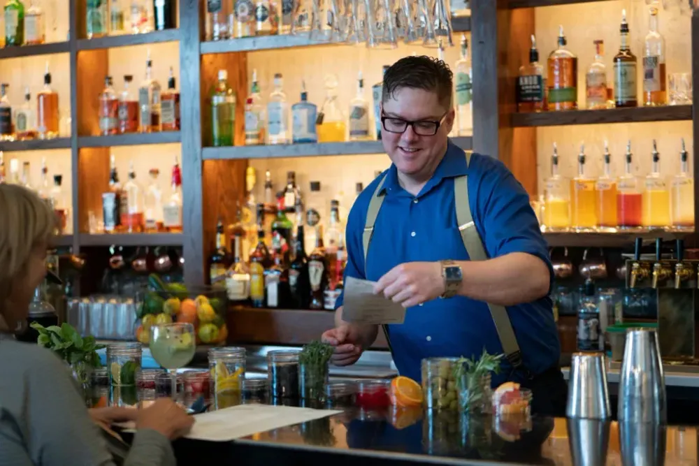 Bartender taking an order from behind a well stocked bar